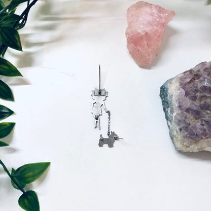 Vintage silver-tone Betty Boop pin with dog charm alongside rose quartz and amethyst crystals on white background with greenery