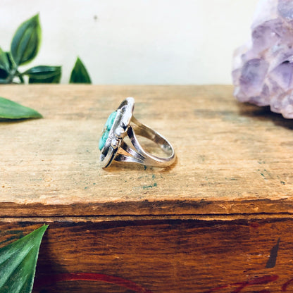 Vintage turquoise and silver ring with geometric design on wooden surface with leaves and crystal