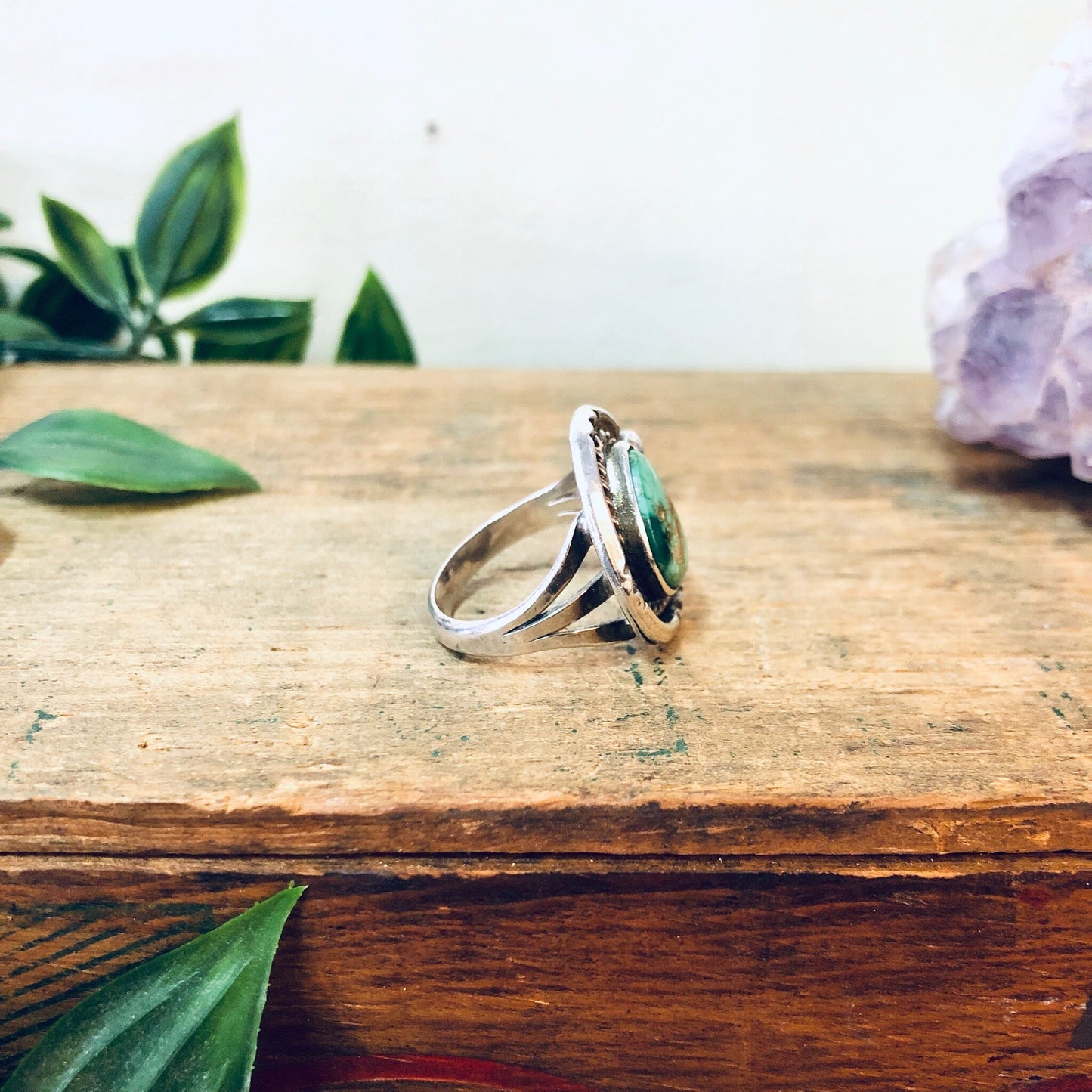 Vintage silver turquoise ring with green stone on wooden surface with leaves