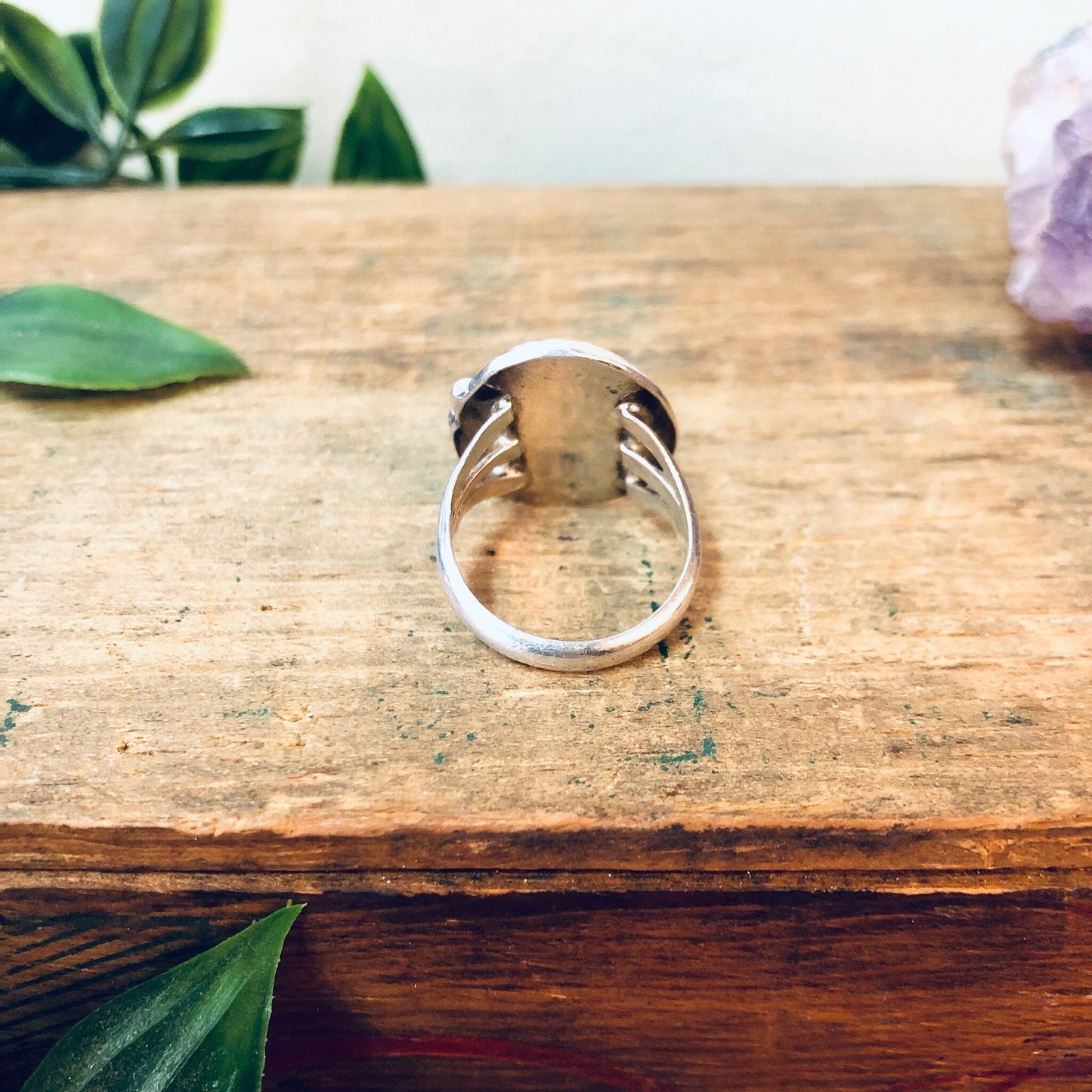 Vintage silver turquoise ring on rustic wooden surface with green leaves