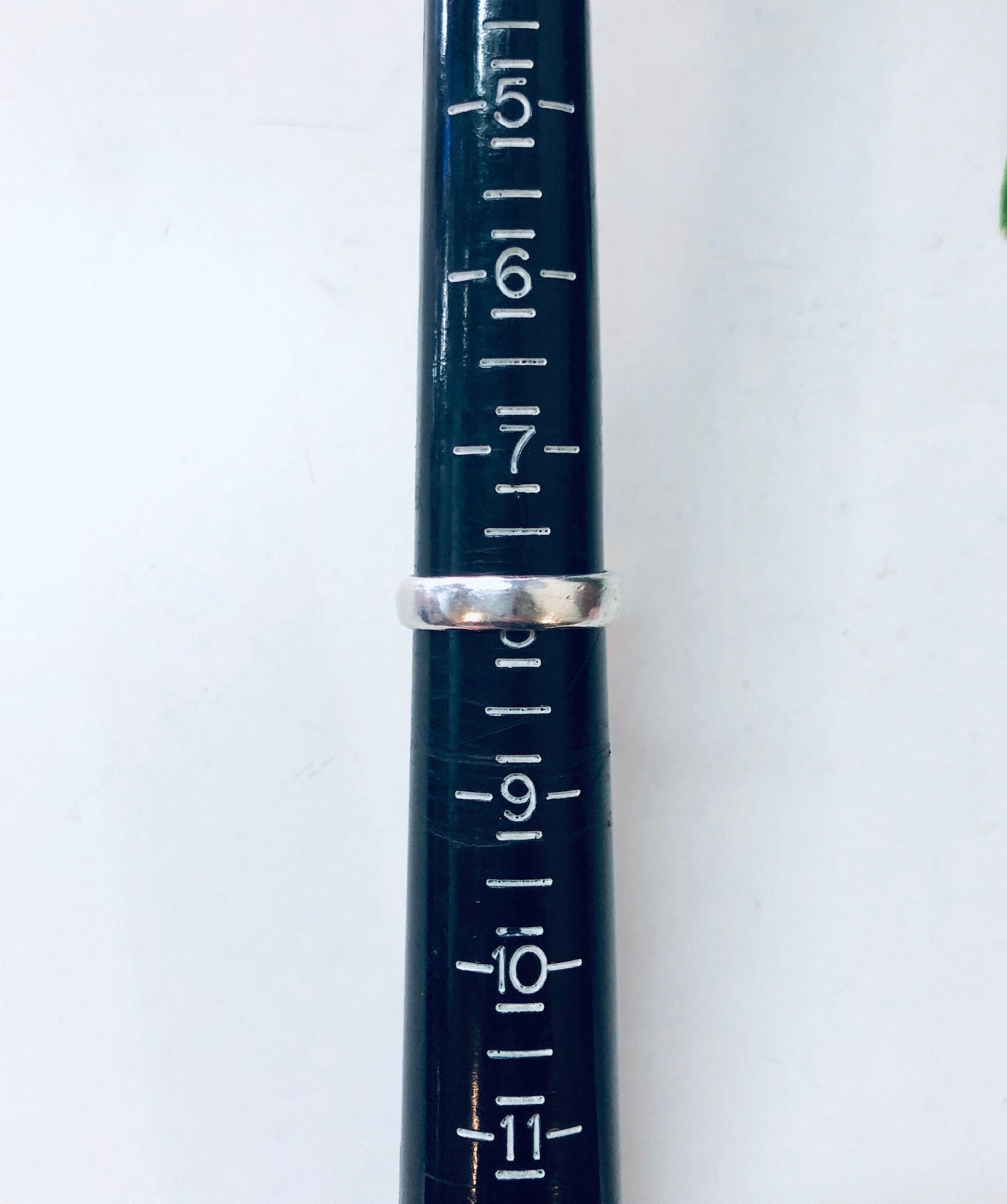 The image shows a close-up view of a vintage metal ruler marked with white measurement lines and numbers. The ruler appears to be well-used, with a slightly tarnished metallic blue finish.