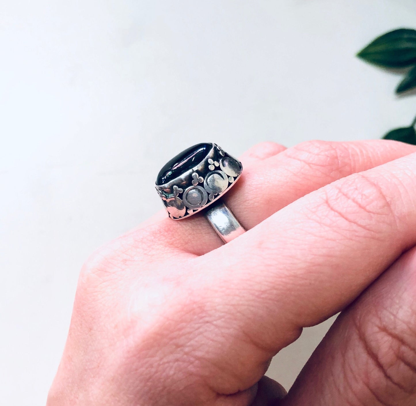 Black onyx and sterling silver vintage-style statement ring displayed on a finger against a plain background.