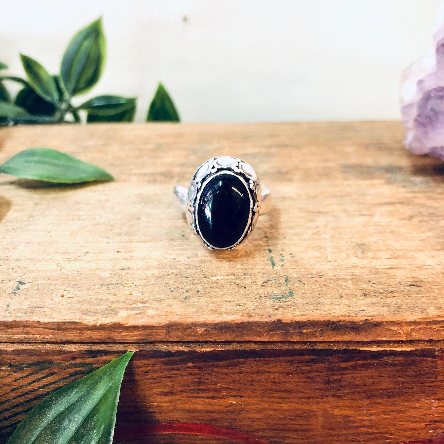 Vintage silver onyx ring on wooden surface with leaves