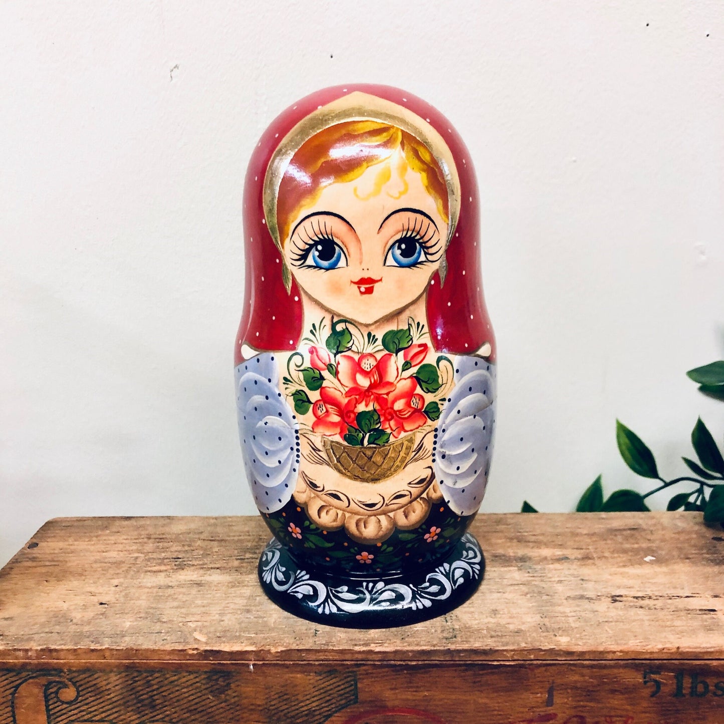 Colorful vintage Russian nesting doll with floral design and blue accents, sitting on a wooden surface.