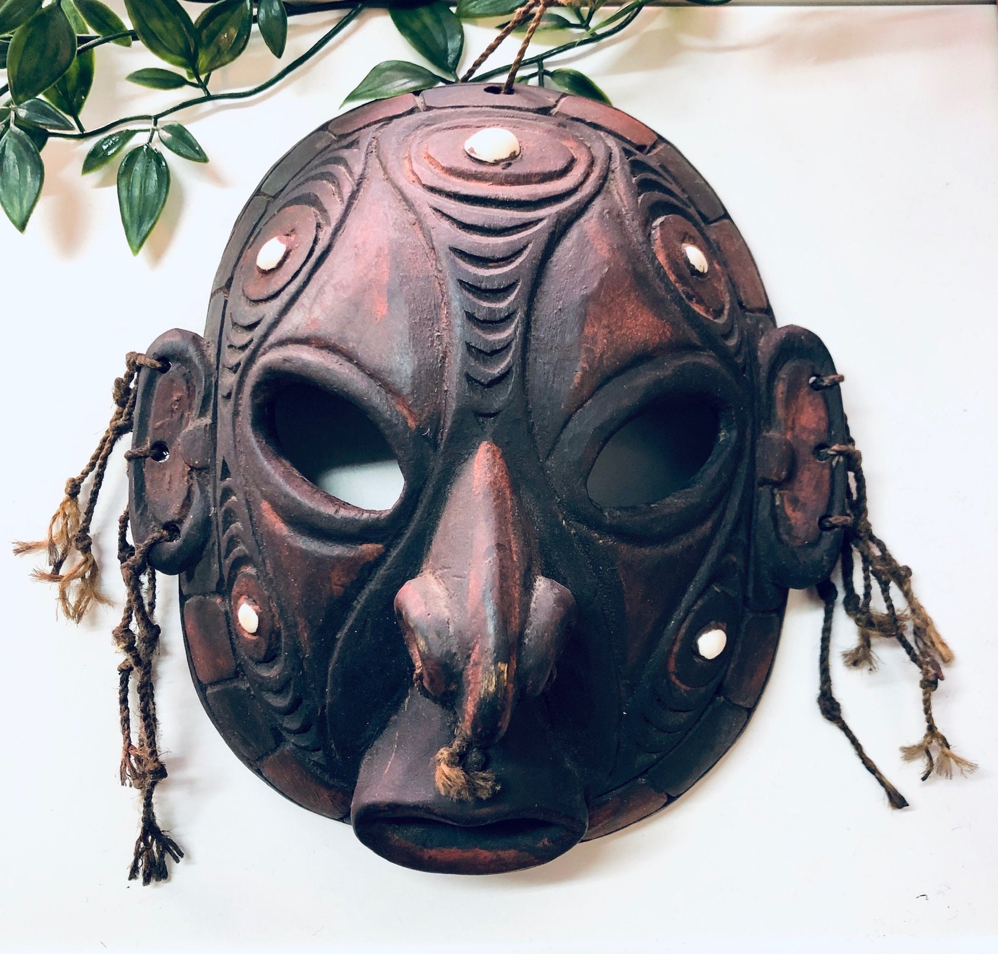 Vintage hand-carved wooden mask with cut-out details, dark finish and tribal design. Unique wall hanging home decor and art piece.