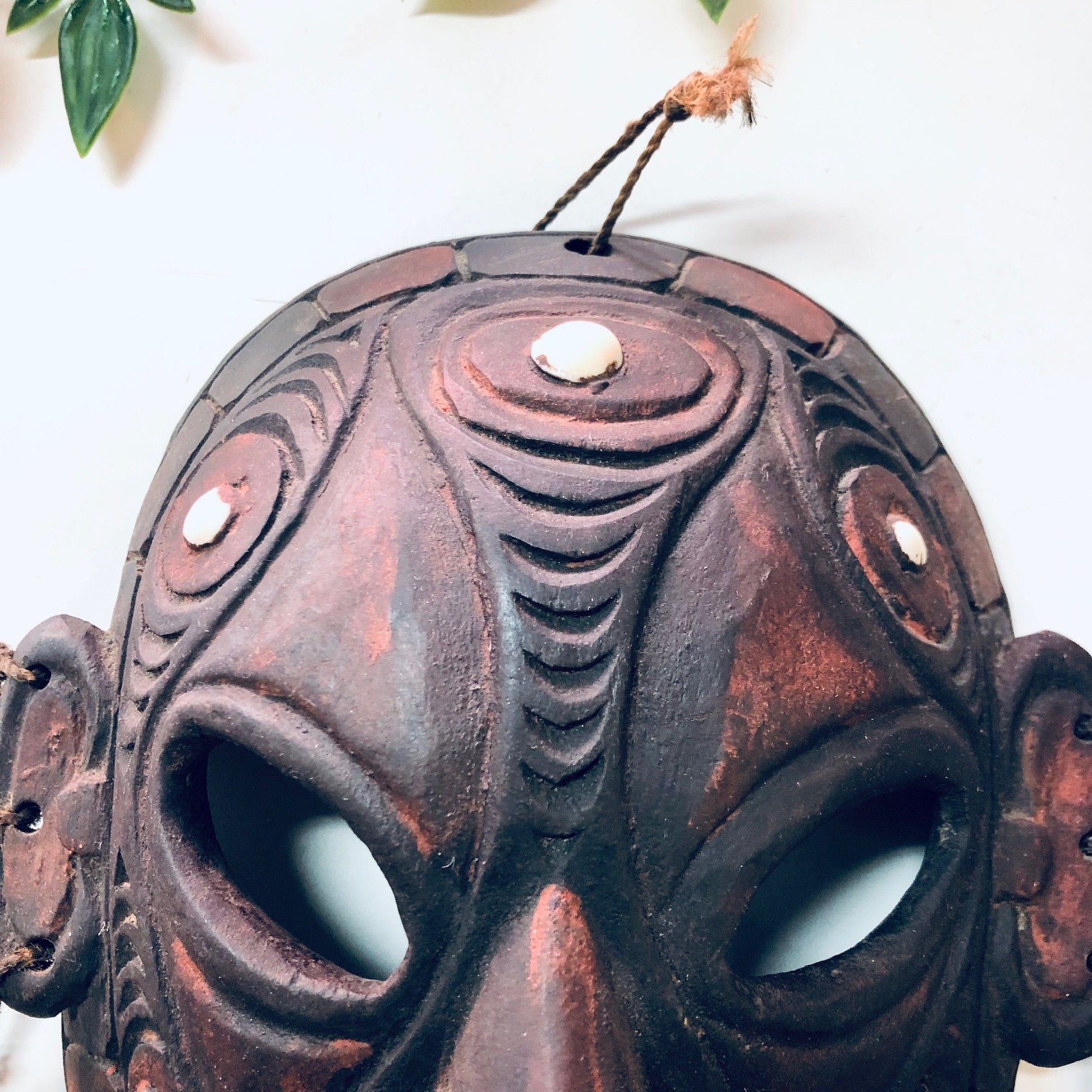 Vintage hand carved wooden tribal mask with intricate spiral designs and cut out details, used as unique wall hanging home decor art piece.