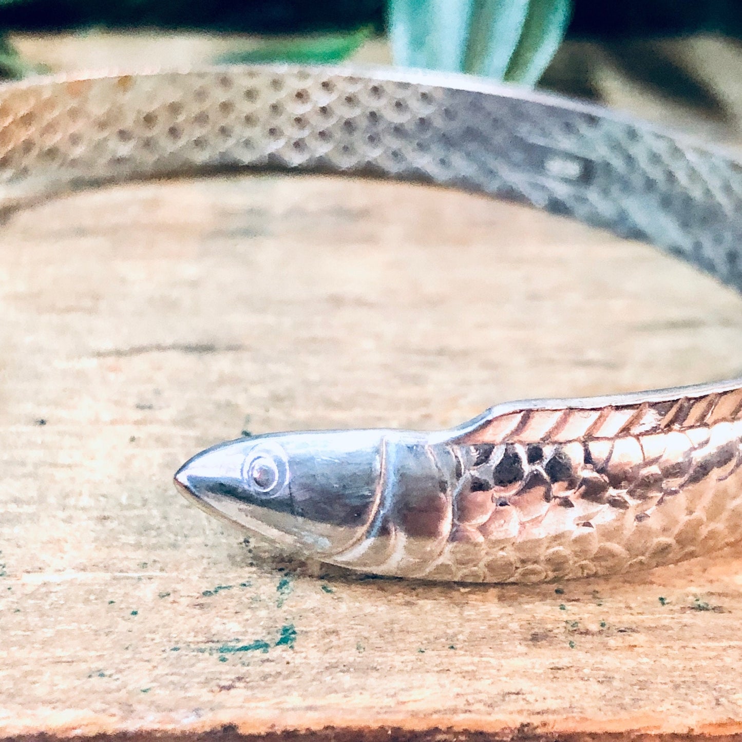 Vintage silver fish bangle bracelet on wooden surface, unique aquatic animal jewelry