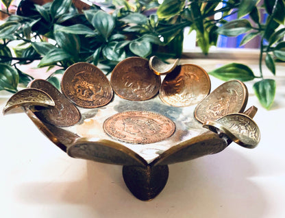 Vintage Mexican coin ashtray or catch-all dish made from copper centavos, surrounded by greenery