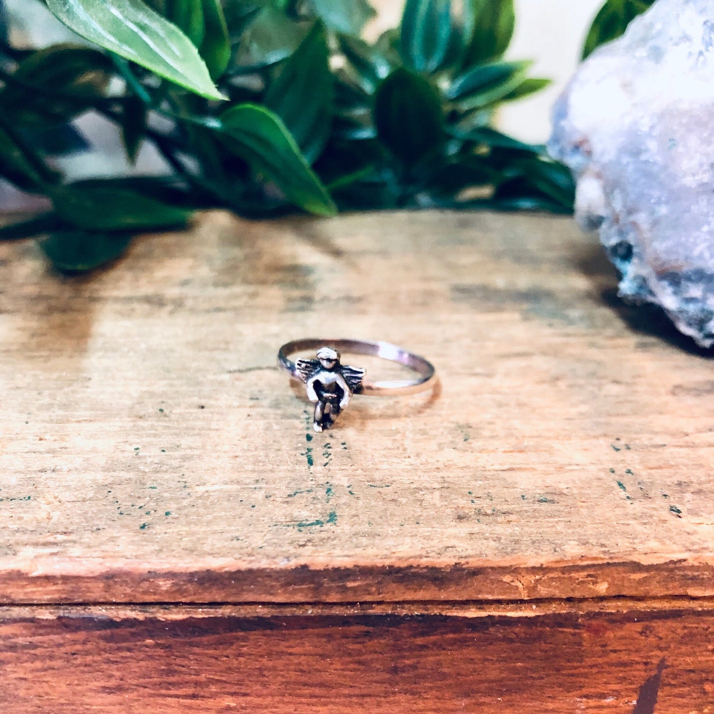 Vintage silver cherub angel ring on wooden surface next to crystal