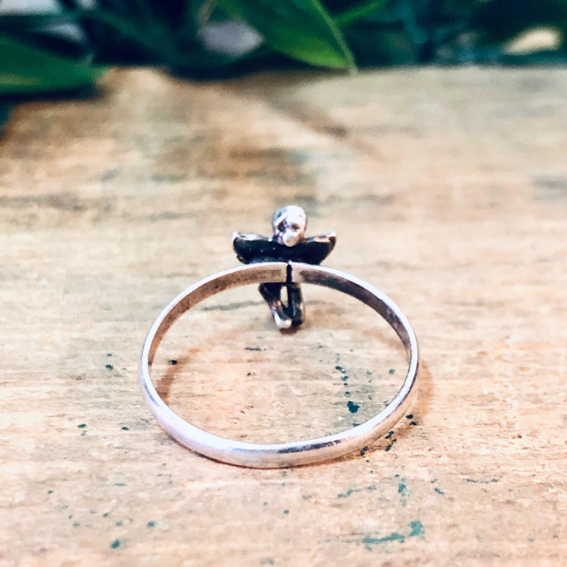 Vintage silver cherub angel ring on rustic wooden surface with foliage in background, ideal Valentines Day gift or angelic jewelry piece.