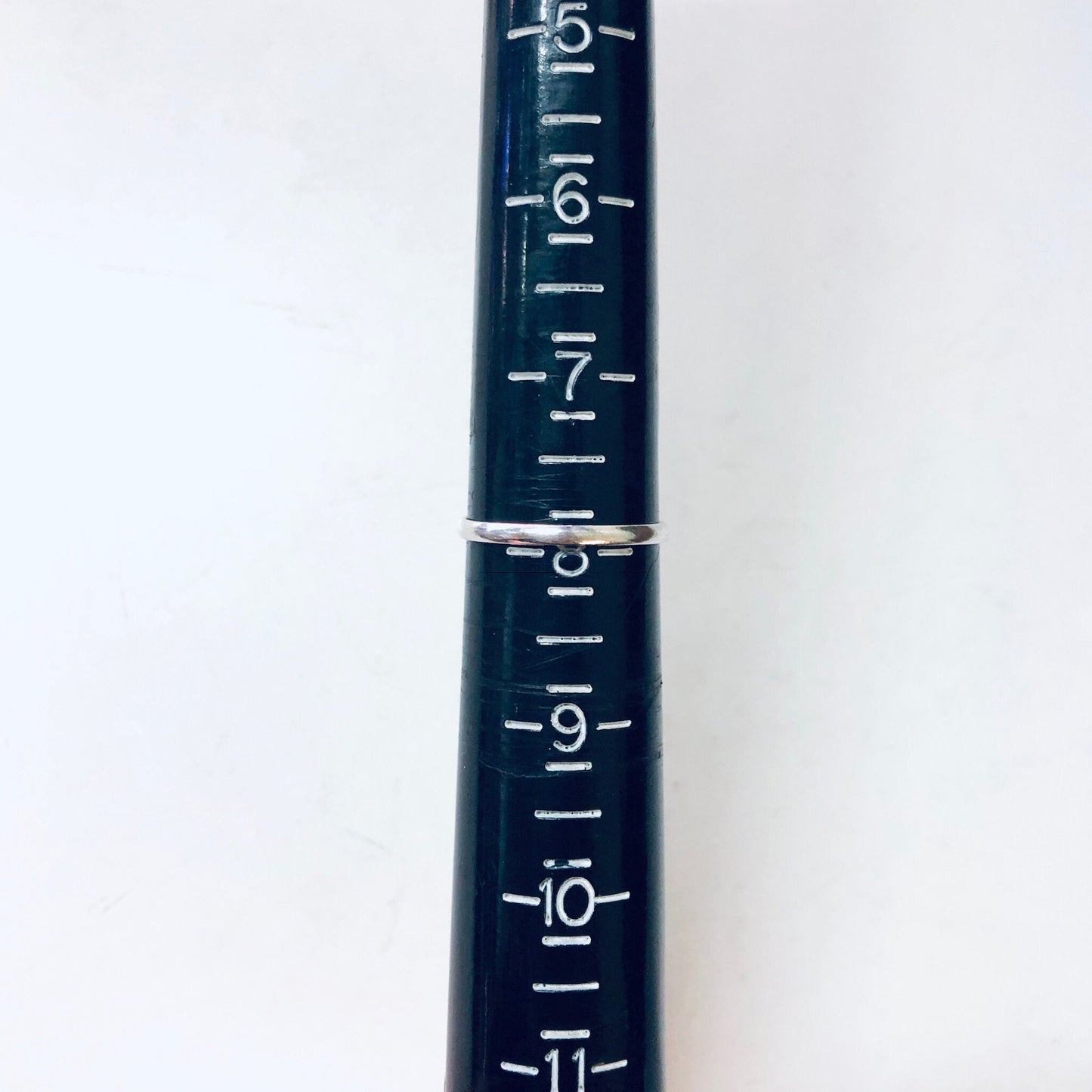 Close-up view of dark blue metal ruler with white markings for measurements from -5 to -11