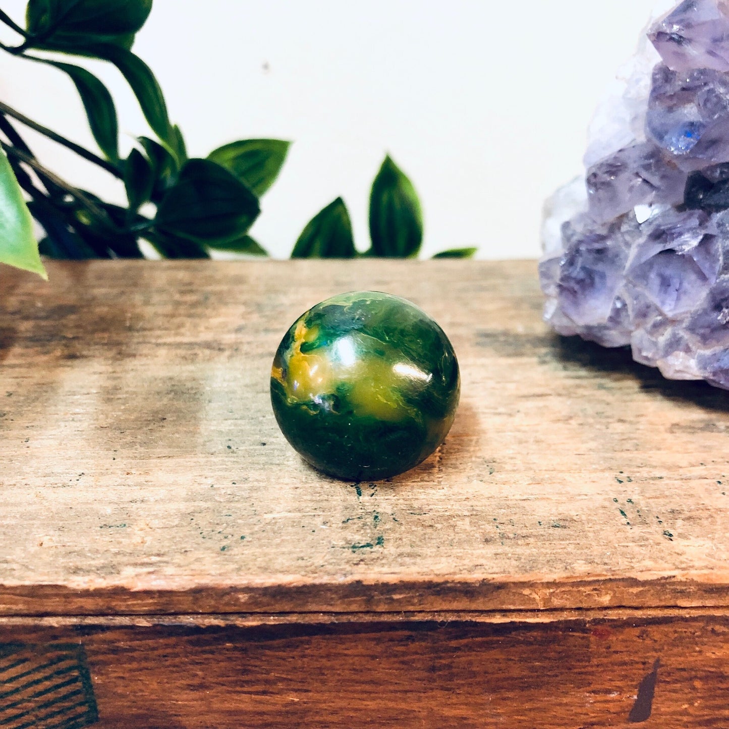 Green marble ball ring on wooden surface with amethyst crystal and plant leaves in background, vintage retro jewelry gift idea for Valentine's Day or statement accessory