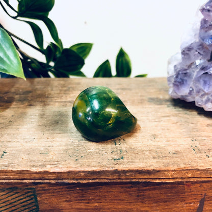 Green marbled plastic ball ring on wooden surface with amethyst crystal and plant leaves in background, retro vintage statement jewelry gift idea for Valentine's Day