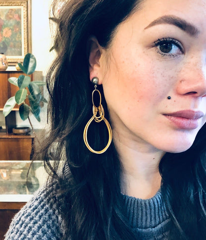 Close-up portrait of a young woman with dark hair, freckles and gold hoop earrings looking to the side