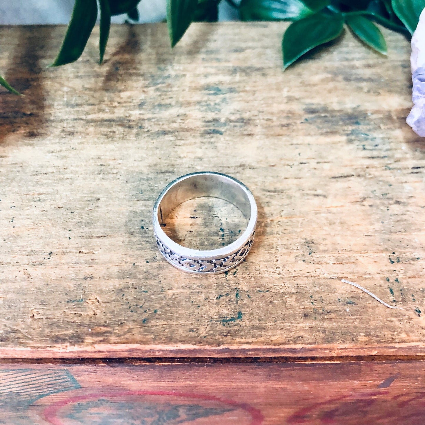 Vintage silver band ring with unique design on rustic wooden surface, surrounded by green leaves. Bohemian style jewelry, perfect as a simple gift for mom or anyone who loves boho fashion accessories.