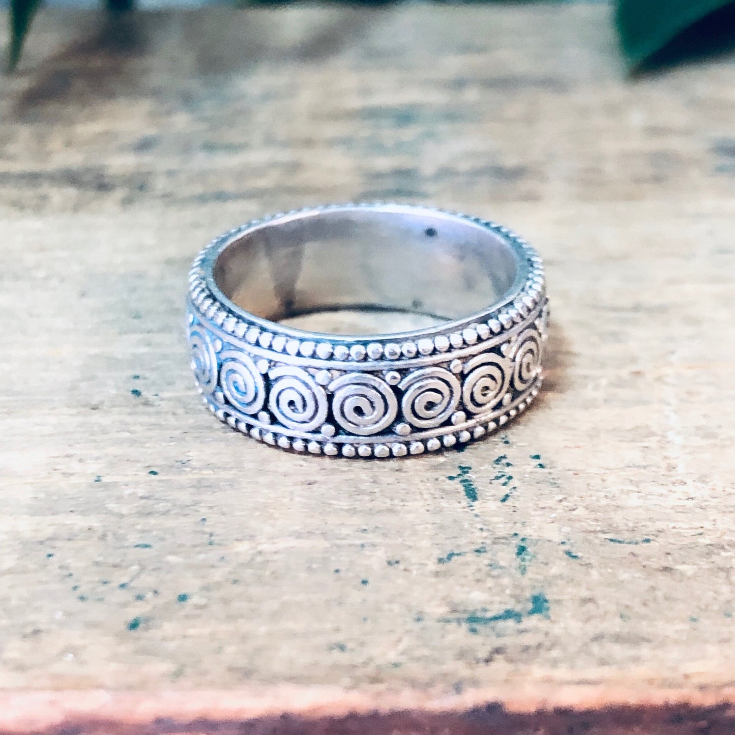 Vintage silver swirl design band ring on worn wooden surface