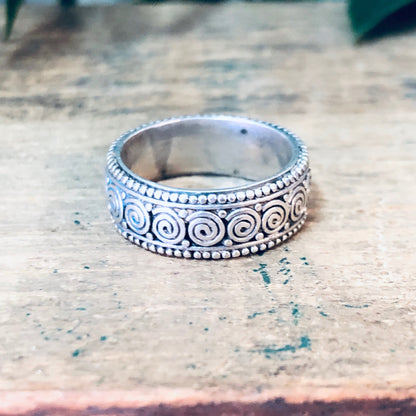 Vintage silver swirl design band ring on worn wooden surface