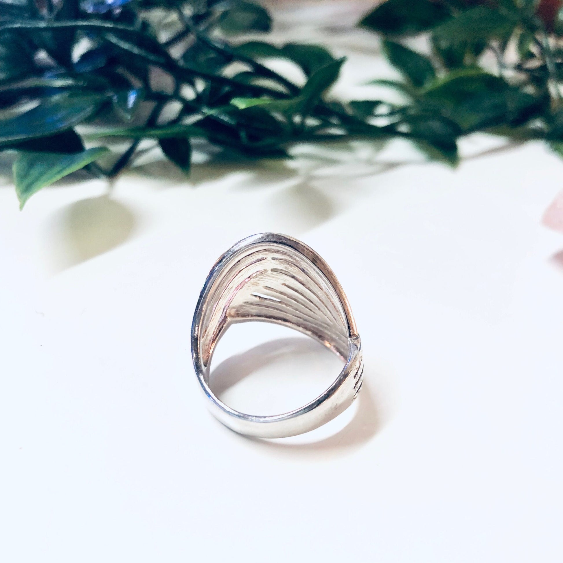 Vintage silver wave design ring made in Thailand, 925 sterling silver, unique sparkly statement jewelry piece with leafy green plant in soft focus background.