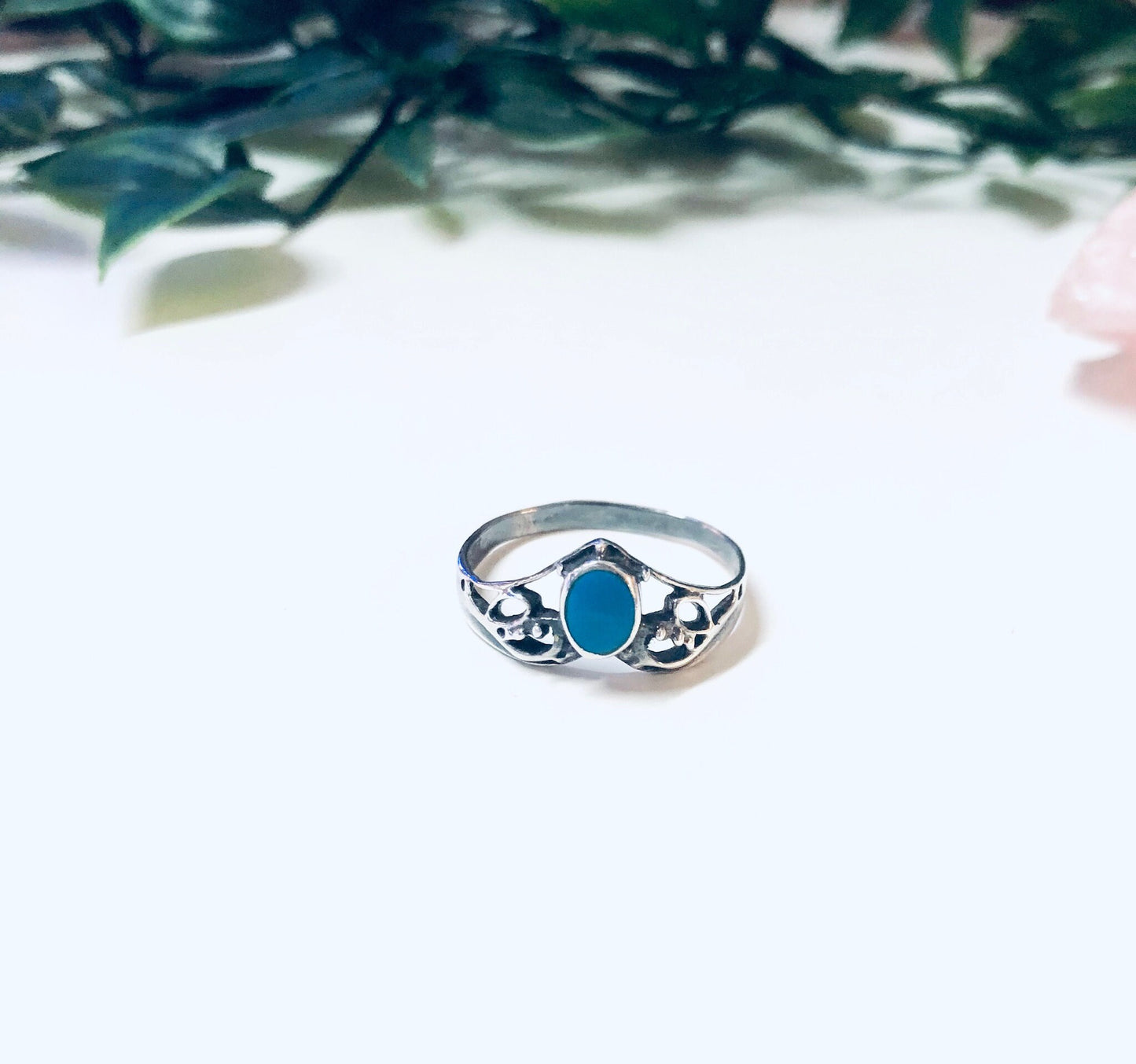 Vintage silver turquoise stacking ring with blue oval-shaped stone set in V-shaped band, displayed on white surface with greenery in background, bohemian style 925 silver jewelry.