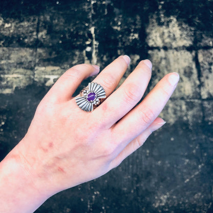 Vintage silver ring with purple gemstone in a unique fan design, worn on a hand against a grungy background, showcasing boho-style statement jewelry made of 925 silver.