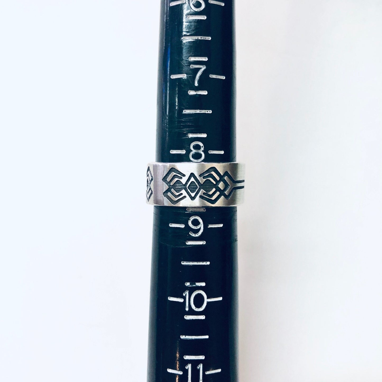 Vintage silver tribal design band ring, thick geometric silver statement jewelry made of 925 sterling silver, shown on a dark blue measuring tape ruler for scale reference.