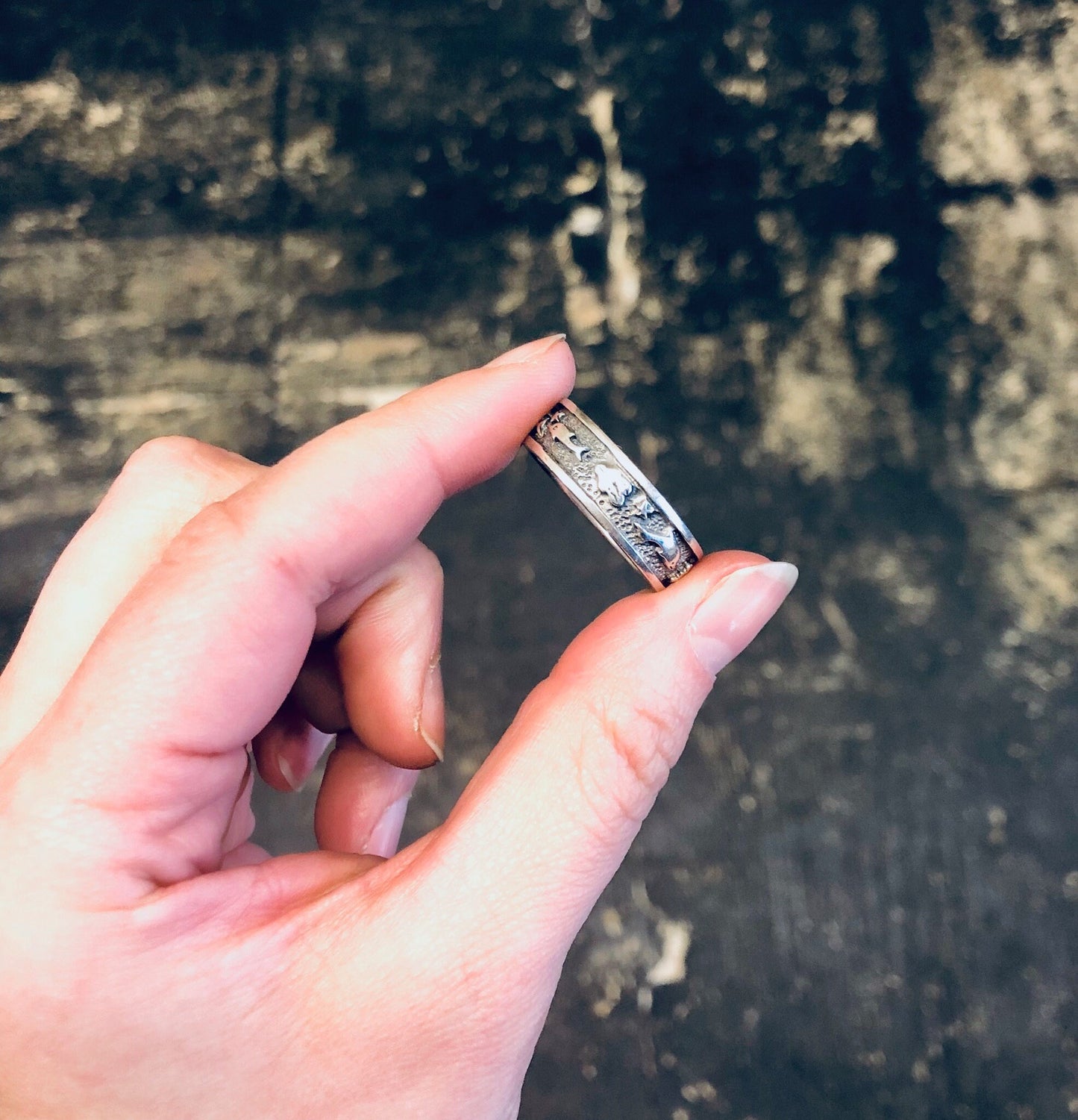 Vintage silver dolphin ring on hand against distressed wooden background