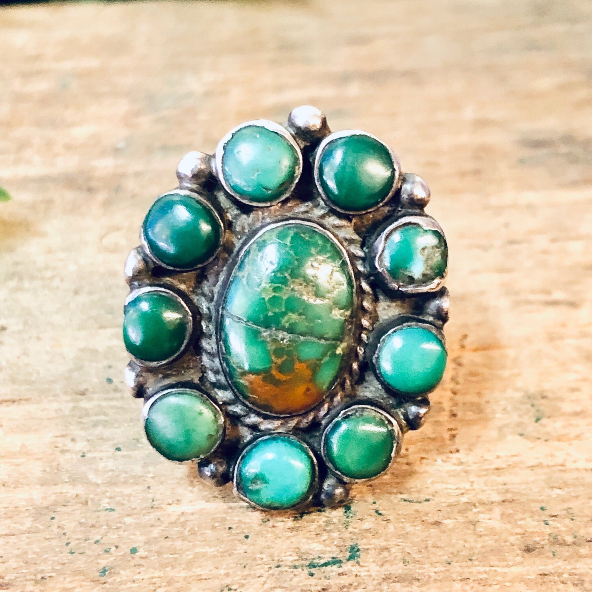 Large vintage silver ring featuring multiple round green turquoise cabochons arranged in an ornate cluster setting, showcasing a bold bohemian southwestern style statement jewelry piece.