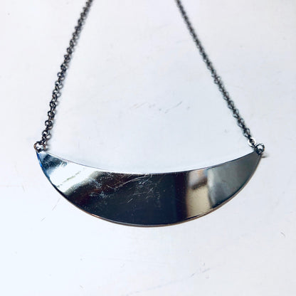 Silver curved panel pendant necklace on chain against white background