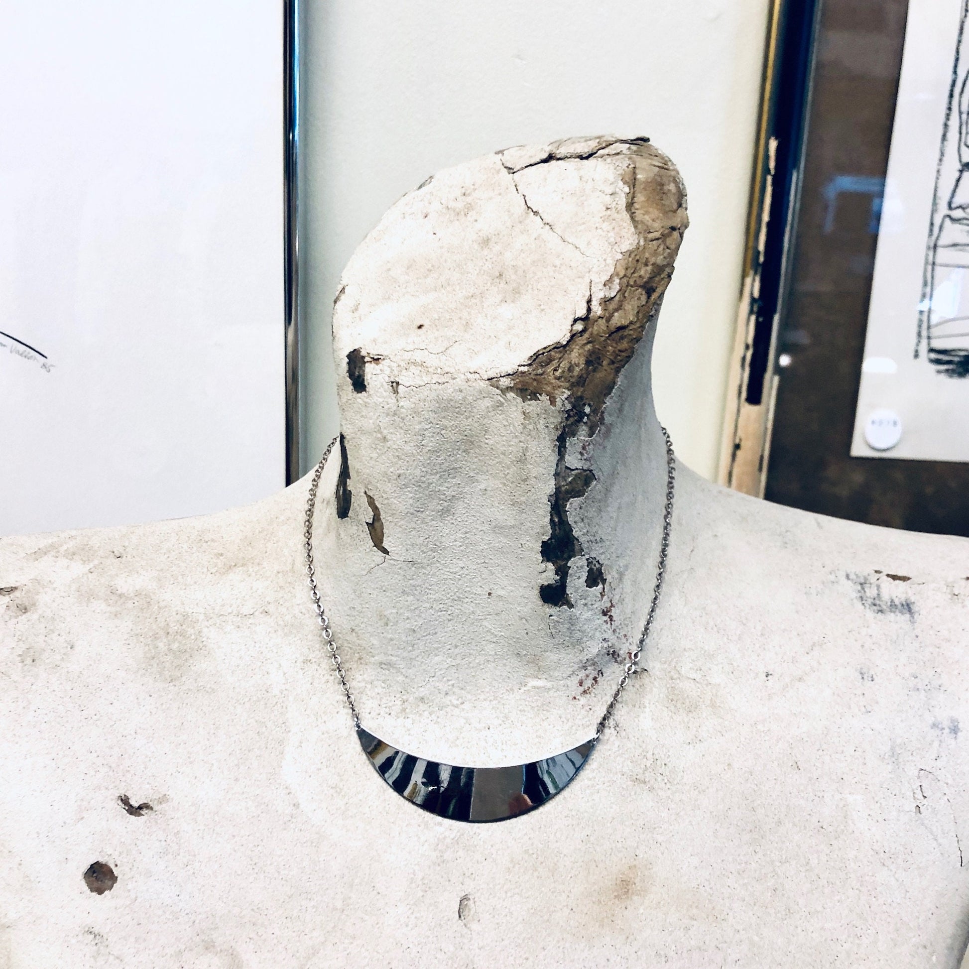 A damaged vintage mannequin with a cracked and broken torso, revealing the hollow interior structure, situated in a deteriorating room setting.