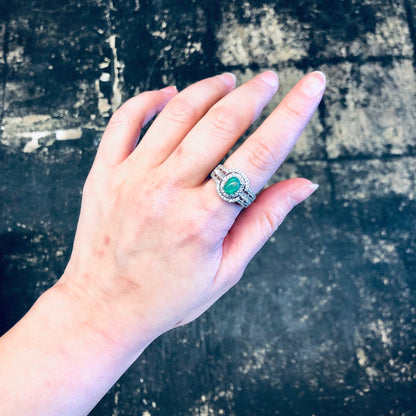 Vintage silver ring with green opalescent stone and faux diamonds on hand against distressed background