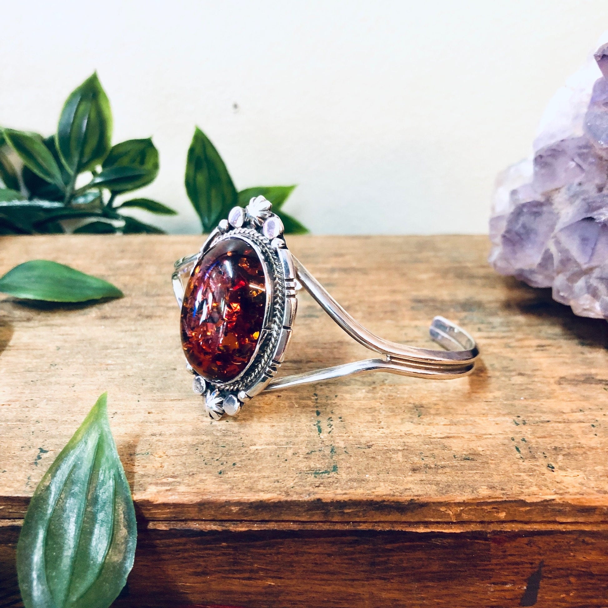 Vintage amber and silver cuff bracelet with orange gemstone on wooden surface with green leaves, perfect Valentines Day or anniversary gift for wife or girlfriend