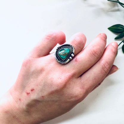 Vintage silver and turquoise ring with Southwestern Boho style, worn on a hand against a white background.