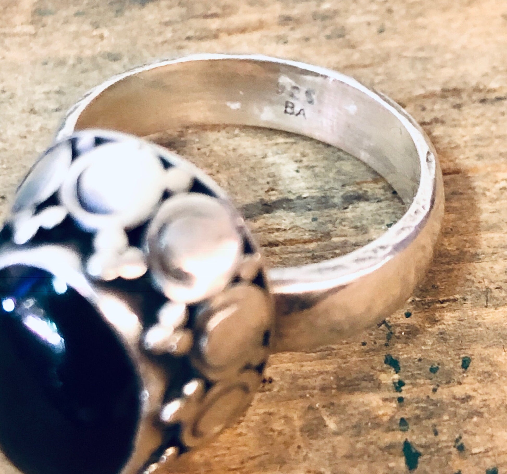 Vintage silver ring with a large black onyx gemstone on a weathered wooden surface.