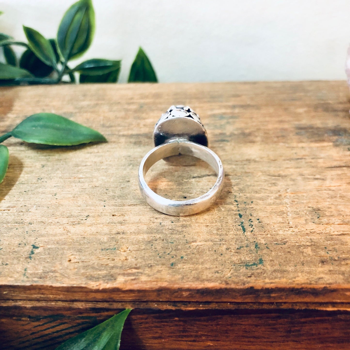 Vintage silver onyx ring on wooden surface with green leaves