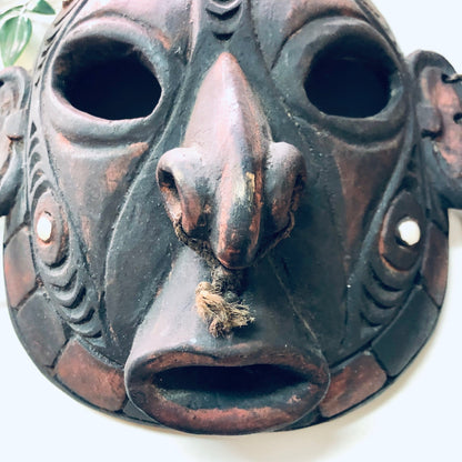 Vintage hand carved wooden tribal mask with cut out features, worn patina, and intricate details, suitable for unique wall decor or art display.