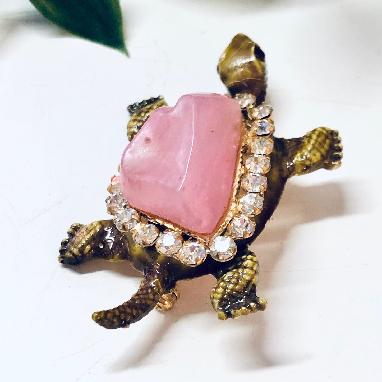 Vintage gold-toned turtle brooch pin with pink gemstone shell and rhinestone accents, an eye-catching piece of animal jewelry from the past.