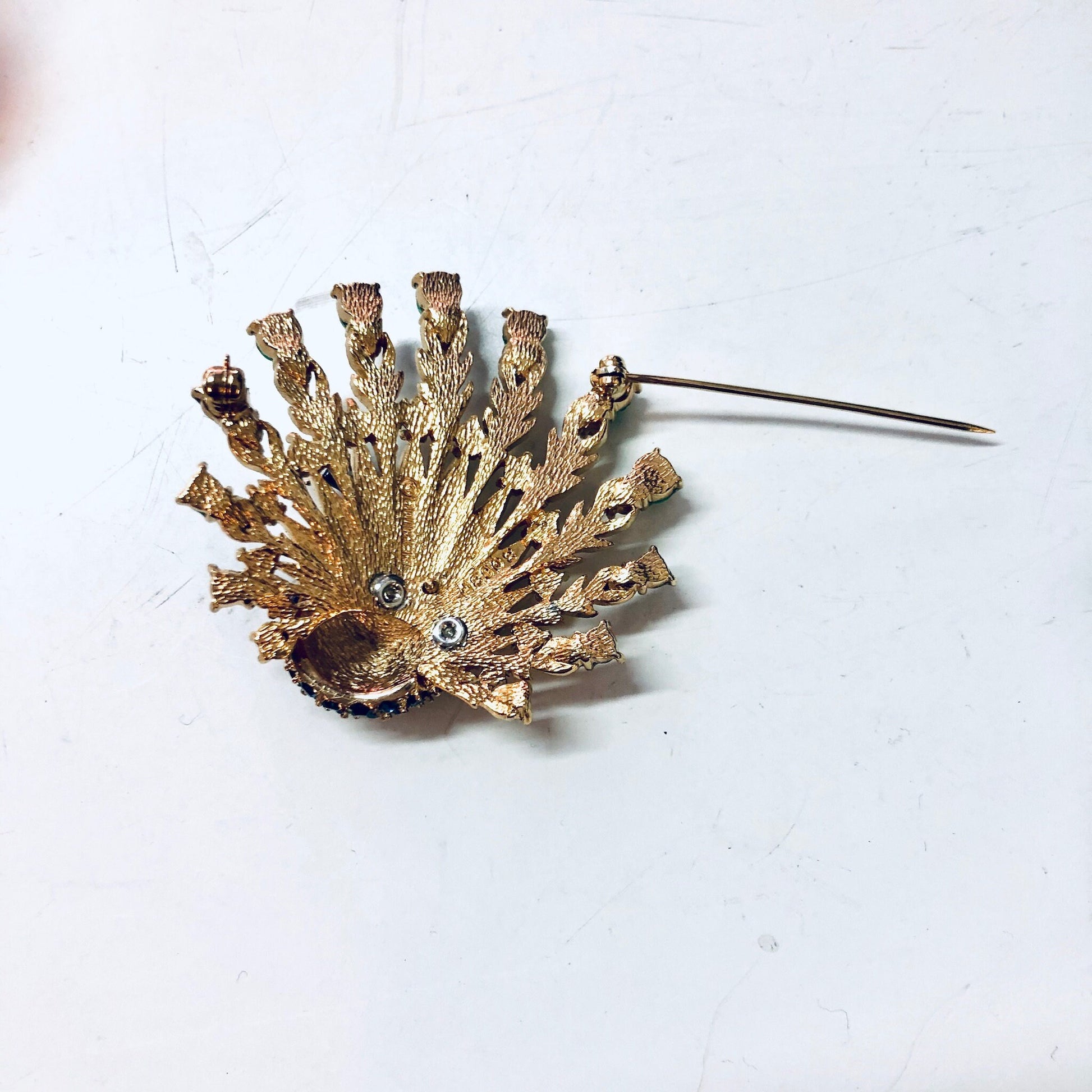 Gold peacock pin brooch with feather detail and blue gemstone accents, vintage costume jewelry by Boucher.