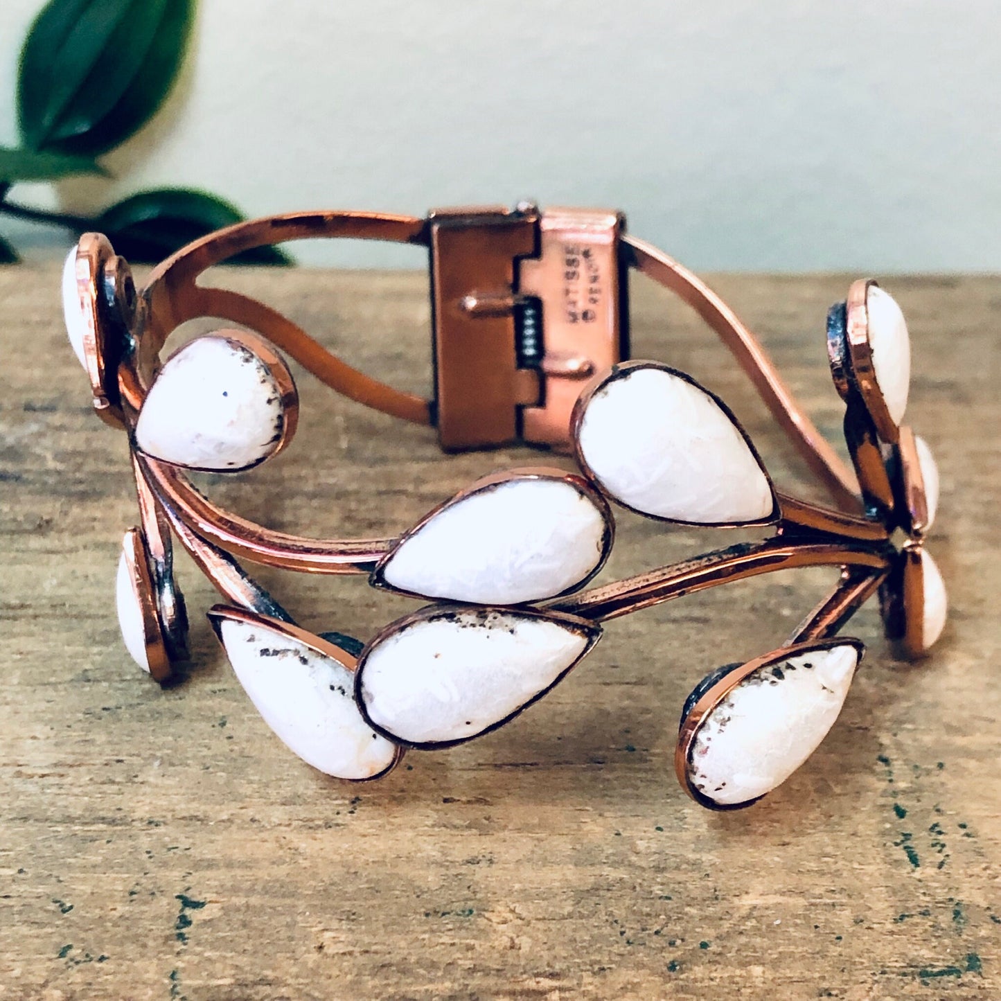 Vintage copper Matisse jewelry set with white enamel leaf design featuring a hinged cuff bracelet and matching brooch on a weathered wooden surface.