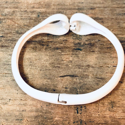 White vintage Vendome bangle bracelet with unique cut-out design on wooden surface