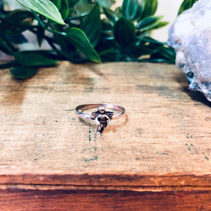 Vintage silver cupid angel ring on wooden surface with crystals and greenery