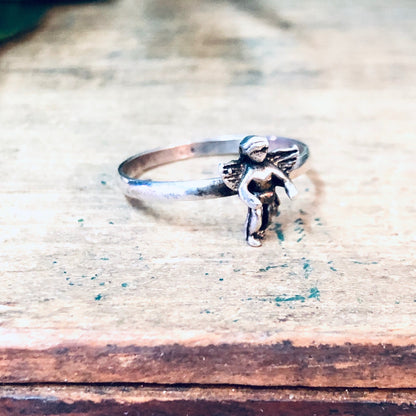 Vintage silver cherub angel ring on rustic wooden surface