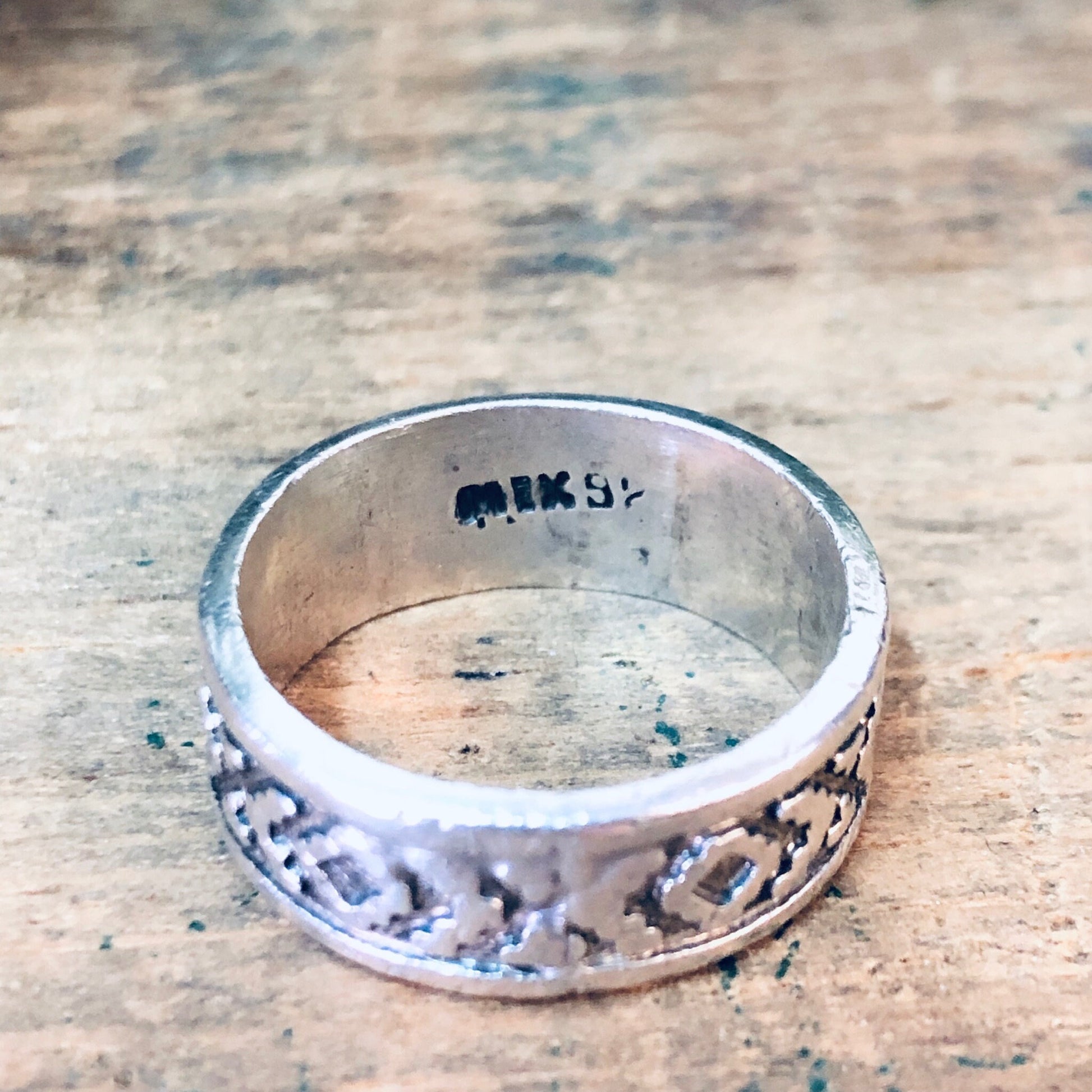 Vintage silver band ring with unique cutout design on textured background