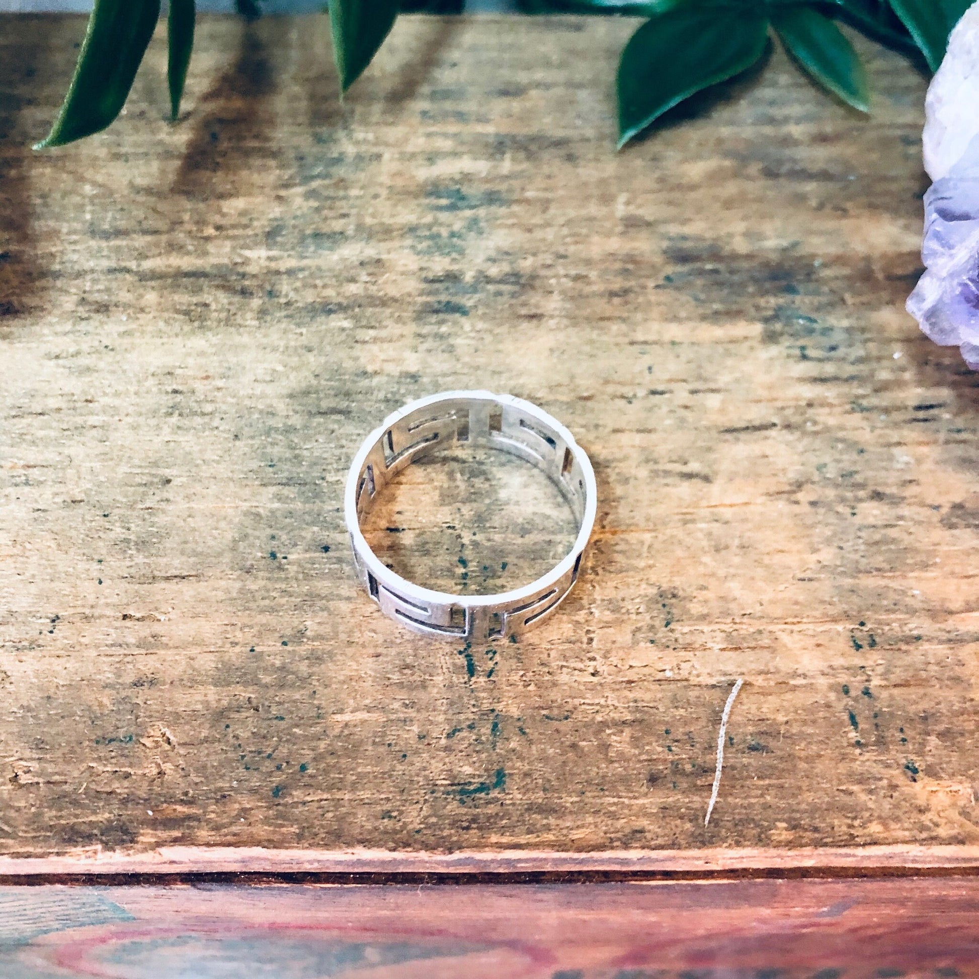 Vintage sterling silver cut out band ring on rustic wooden surface with leaves above