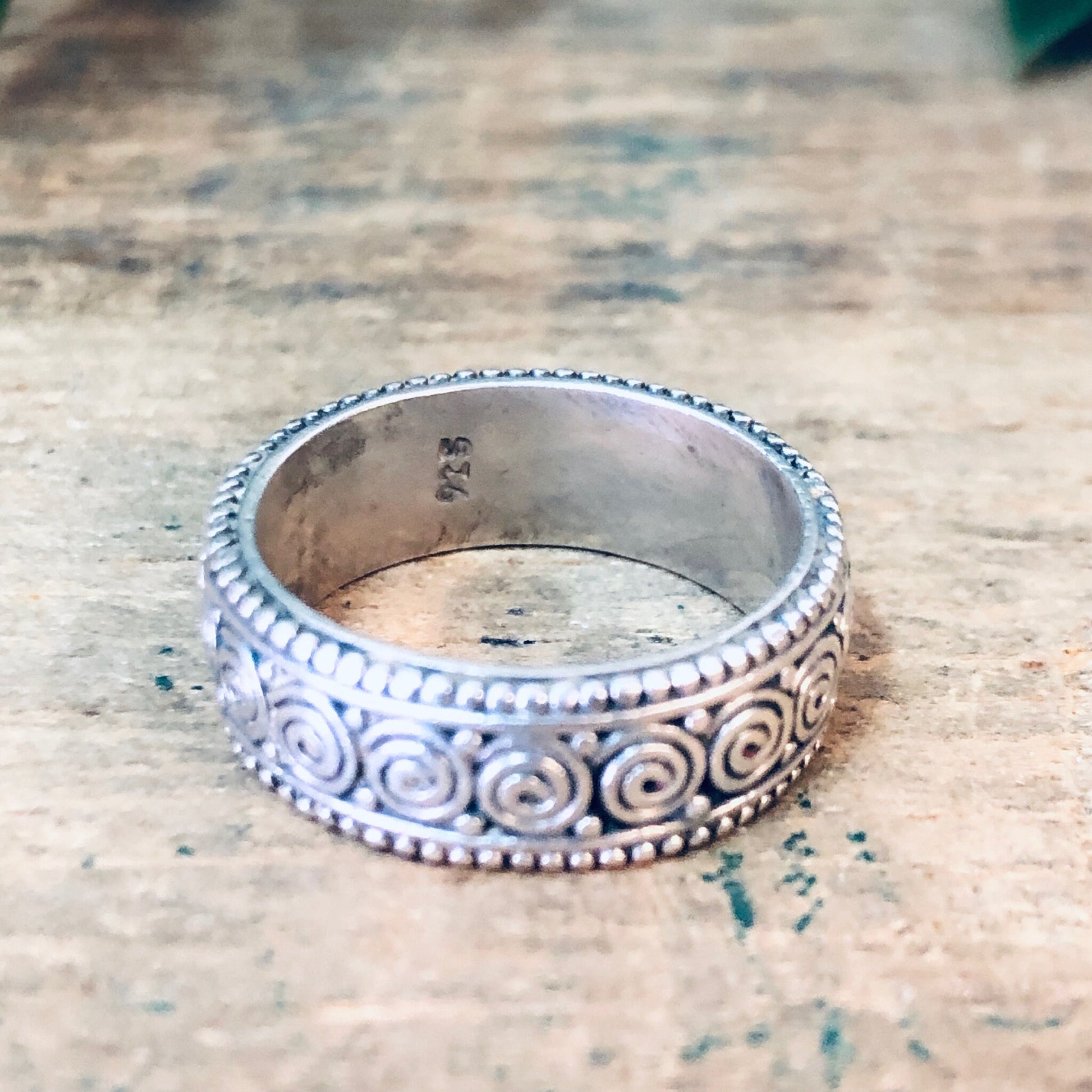 Vintage sterling silver swirl design band ring on rustic wooden surface