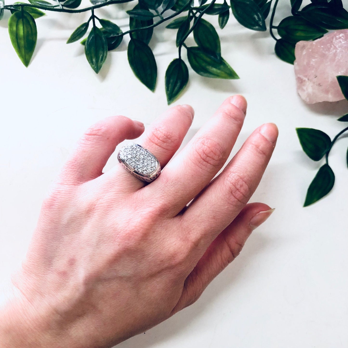 Vintage silver ring with rope design and faux diamond, shown on hand with plant leaves in background