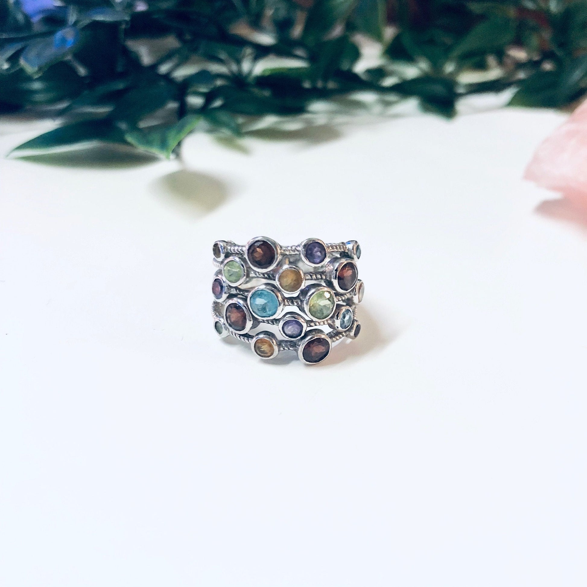 Vintage silver multi-band ring with purple, blue, red, green, and yellow gemstones set in an intricate design, creating a bold and colorful statement jewelry piece.