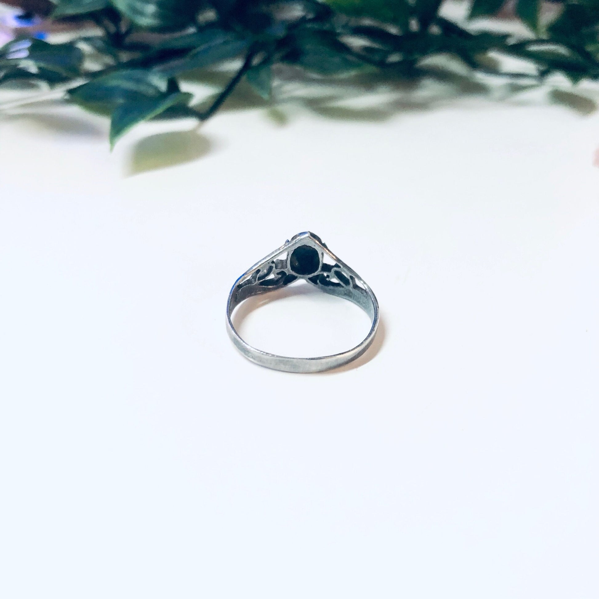 Vintage silver turquoise stacking ring with V-shaped design on white background with green leaves