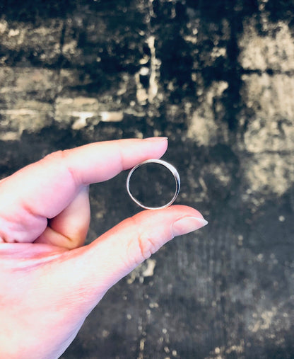 Vintage silver ring held in hand against grungy weathered surface background