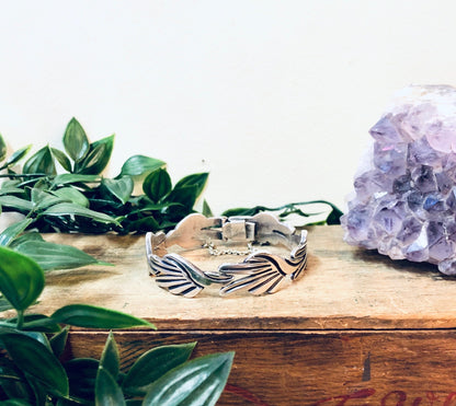 Vintage silver link bracelet from Taxco, Mexico on wooden surface with green leaves and purple crystal geode