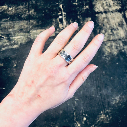 Vintage silver ring with geometric tribal design worn on finger, thick silver band statement jewelry.